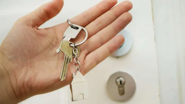 A hand holding keys in front of a door lock