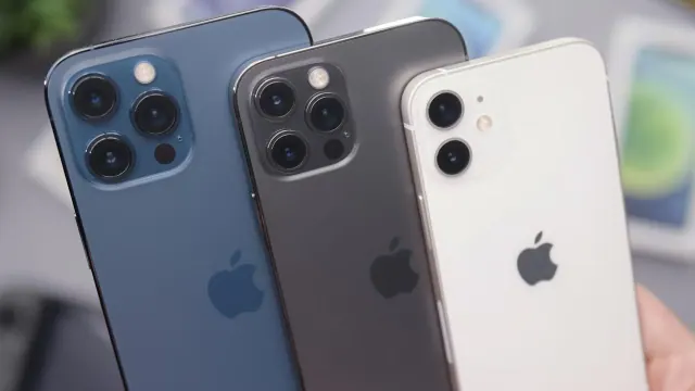 A person holding three iPhones. They vary in size and color. The biggest one is blue, the second is grey, and the smallest is white.