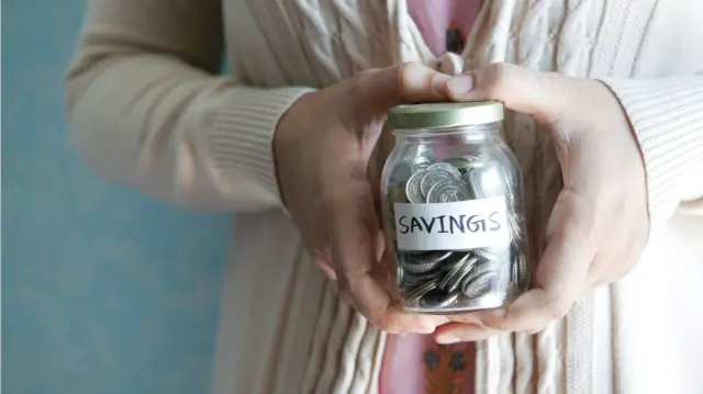Hands holding a jar labeled savings