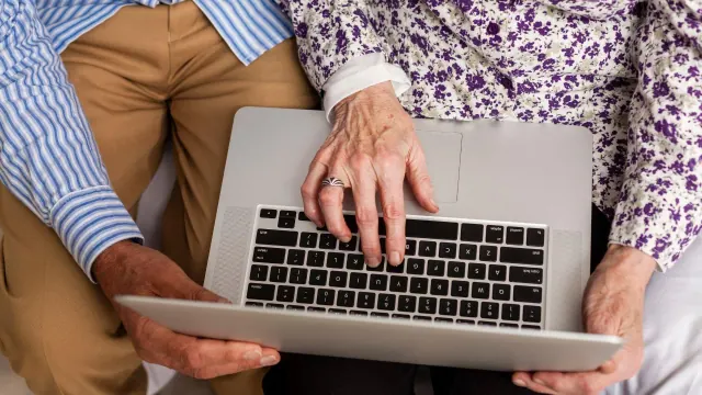 An overhead view of two older people using a laptop