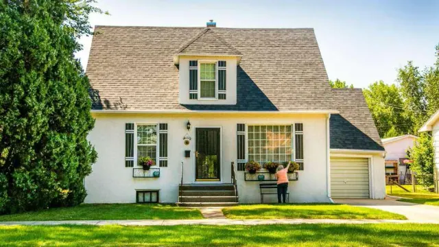 A person standing beside the front window of a house