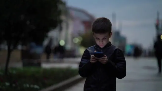 A child looking at a smartphone outdoors