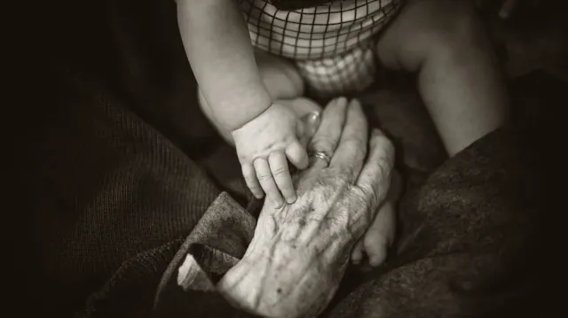 A child’s hand resting on an older person’s hand