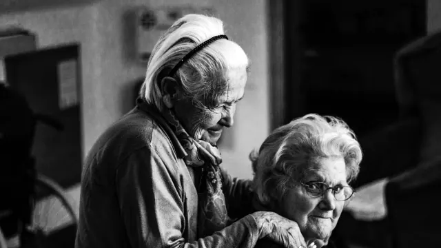 A black-and-white photograph of two older people seated close together