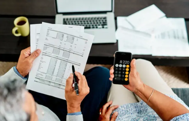 Hands completing paperwork beside a calculator