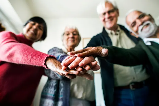 Illustrative group stacking their hands together