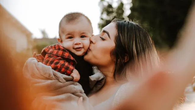 An adult kissing a baby