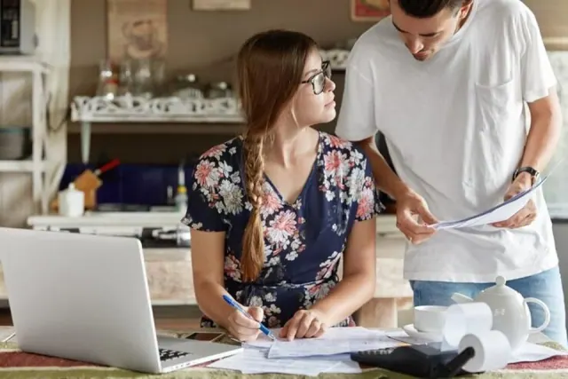 Two people looking at bills in a kitchen