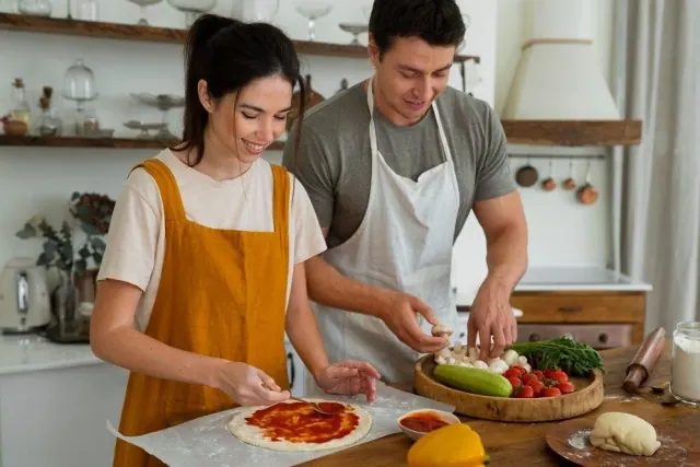 Young couple preparing homemade pizza in their kitchen