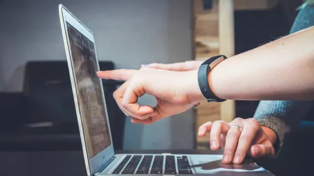 Two people pointing at a laptop screen