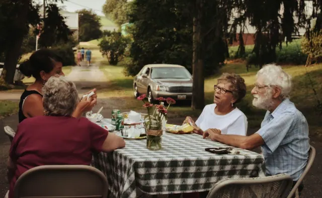 A group of older people sitting outside and eating together.