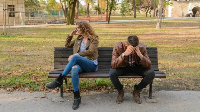 Two people sitting apart on a park bench