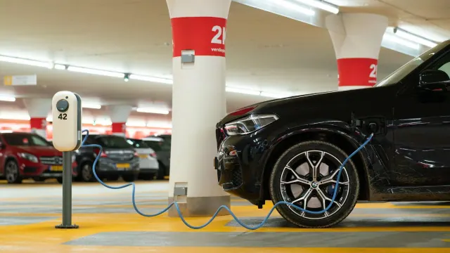 Electric car connected to charging equipment in a parking garage