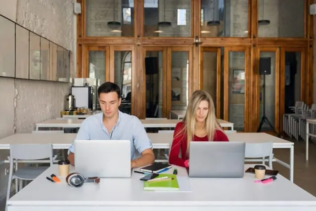 Two people using laptops in an office