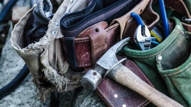 A worn tool belt holding hand tools