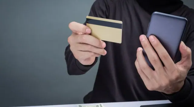 A person holding a card and phone