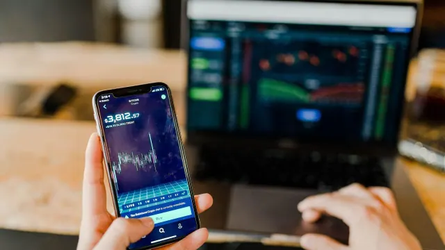A phone displaying a financial chart beside a laptop