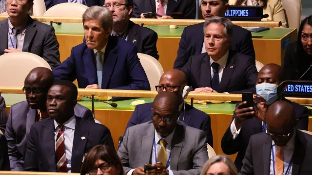 Delegates seated at a meeting, with John Kerry near the center