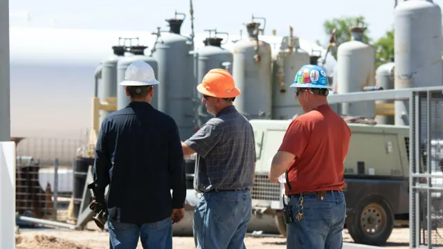 Three people wearing hard hats at an industrial site