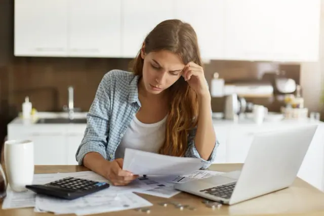 A person reviewing paperwork at a kitchen table