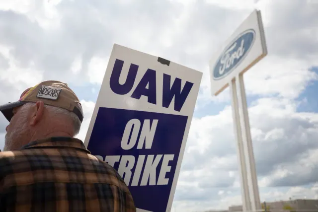 A UAW On Strike sign with a Ford sign in the background