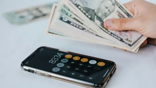Cash beside a phone calculator