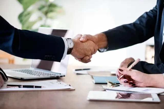 People shaking hands over a desk