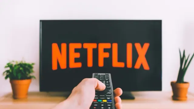 A remote pointed at a television showing Netflix