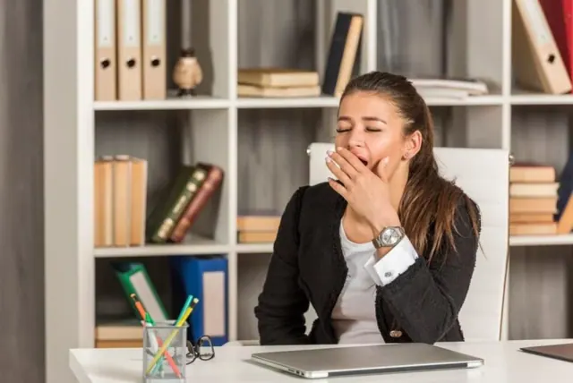 A person yawning beside a laptop