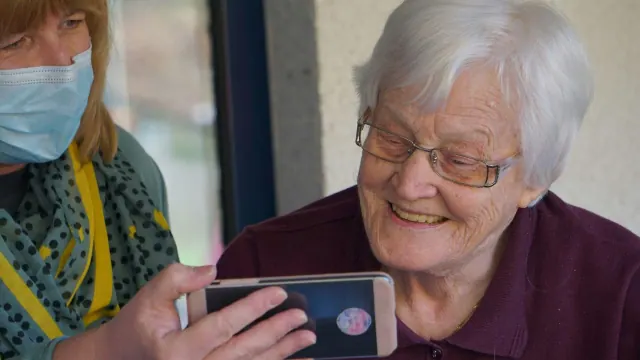 A lady showing an older lady something on her phone.