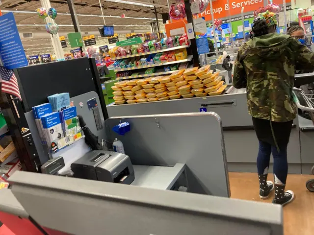 A shopper and groceries at a supermarket checkout