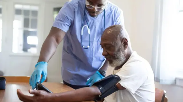A healthcare worker taking an older adult’s blood pressure