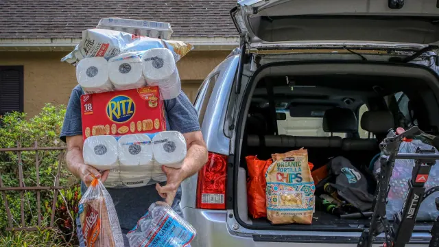 A person loading household shopping into the back of a vehicle