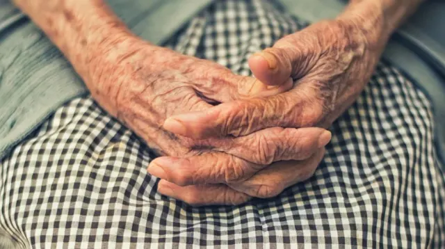 An older adult’s folded hands