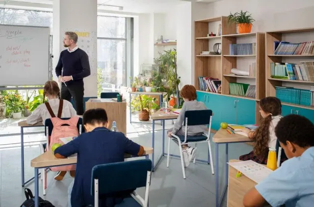 A teacher standing beside students seated in a classroom