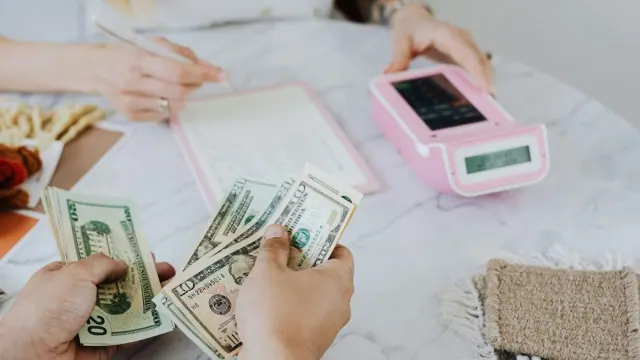 People sorting cash beside a calculator