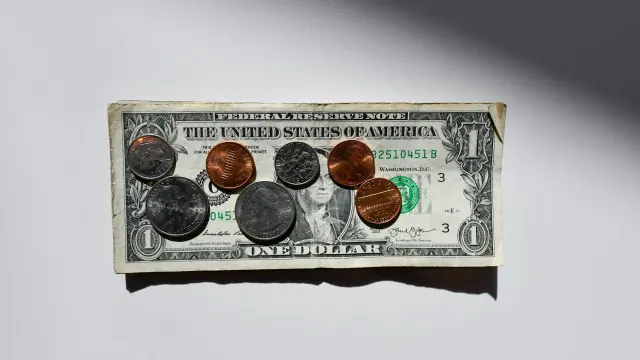U.S. dollar bills and coins on a plain surface