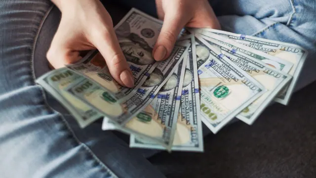 Hands holding a fan of US dollar bills