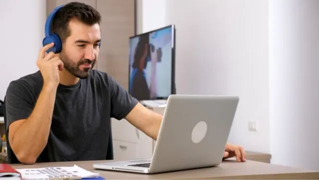 A man is pictured making a video call on his laptop as he works from home