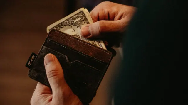 A hand taking cash from a wallet