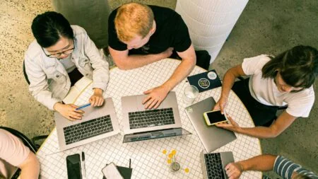 Group of employees working on laptops at table