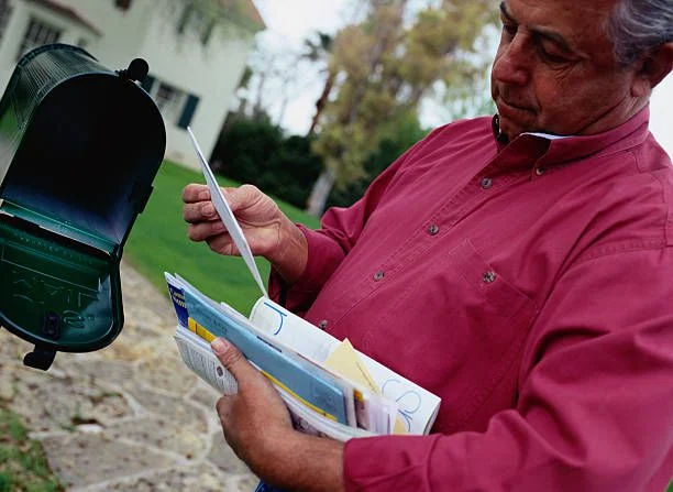 A person checking letters beside a mailbox